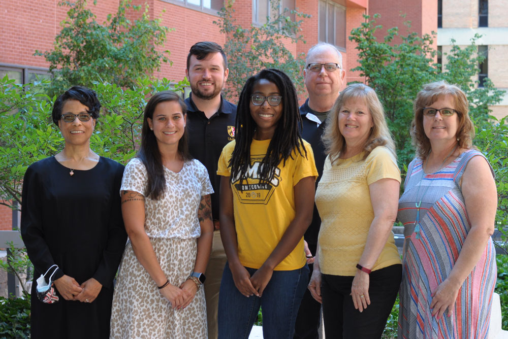 An informal staff portrait of five women and two men who are members of the Academic Engagement and Transition Programs standing outside under a tree.
