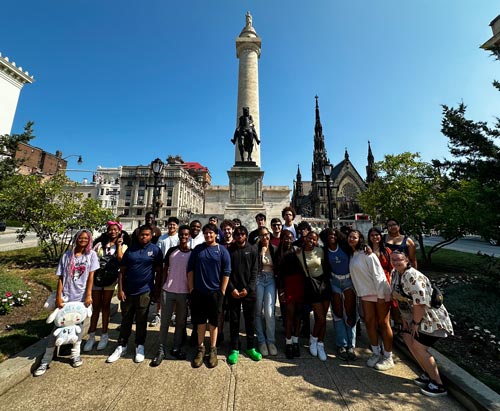 A large group of students posing in front of the Washington monument in Baltimore, Maryland