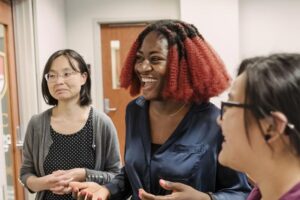 Instructor and two smiling students at a white board teaching a lesson plan.